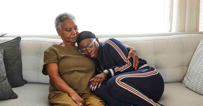 Stock image illustrating cancer shows woman wearing headscarf hugging her mother on the sofa