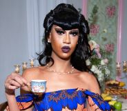 Tia Kofi holding a cup of tea or coffee.