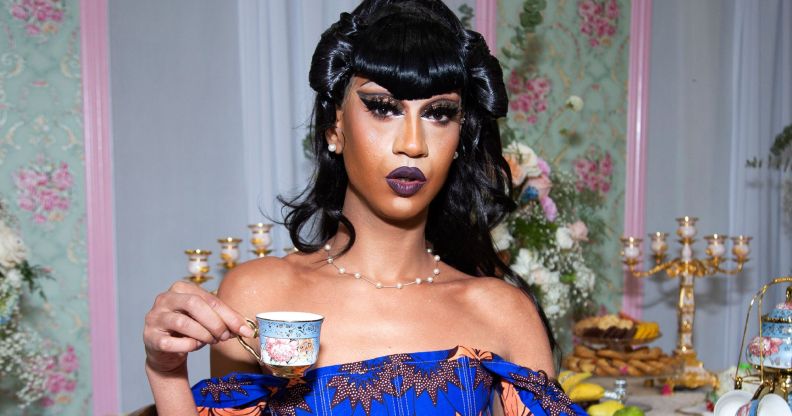 Tia Kofi holding a cup of tea or coffee.