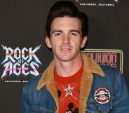 Former Nickelodeon star Drake Bell wears a red shirt and jean jacket as he poses for the camera