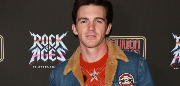 Former Nickelodeon star Drake Bell wears a red shirt and jean jacket as he poses for the camera