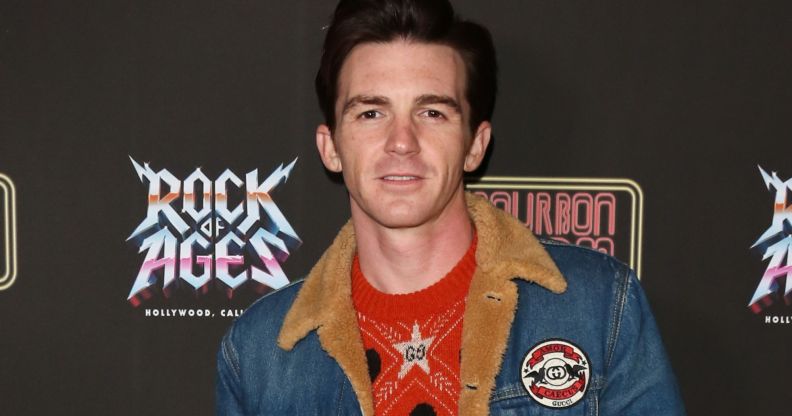 Former Nickelodeon star Drake Bell wears a red shirt and jean jacket as he poses for the camera