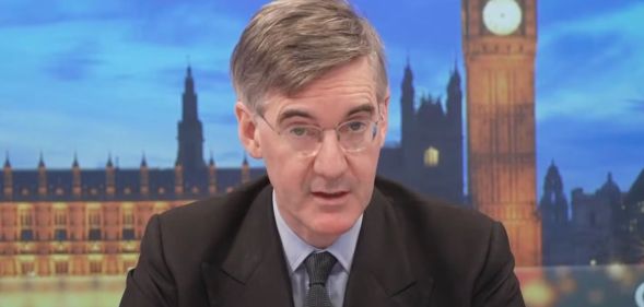 Tory MP Jacob Rees-Mogg sits at the desk as he presents on GB News