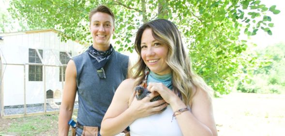 Couple Kristin and Davina smile up at the camera - . Davina, right has long dark hair and Kristin, left, has short dark hair.