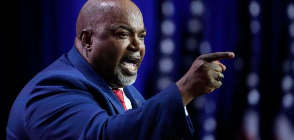North Carolina Republican governor candidate Mark Robinson wears a suit and tie as he points somewhere off camera during a speech
