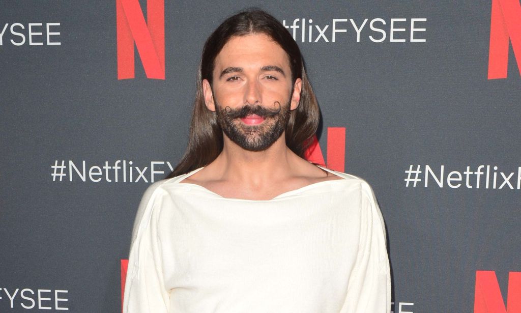 Queer Eye star Jonathan Van Ness looks towards the camera while wearing a white top
