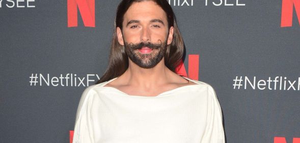 Queer Eye star Jonathan Van Ness looks towards the camera while wearing a white top