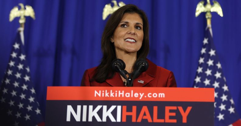 Republican presidential nomination candidate Nikki Haley smiles while wearing a red outfit as she stands in front of podium with her name on it