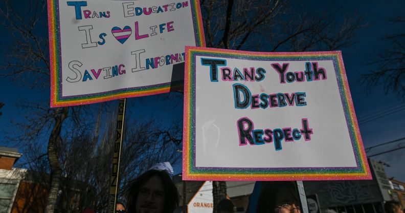 people hold up a sign reading 'trans education is life saving' and 'trans youth deserve respect' as anti-trans bills are proposed across the USA and North America