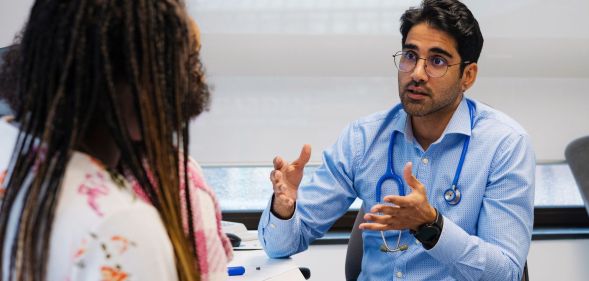 A doctor speaking to a patient in a medical room.