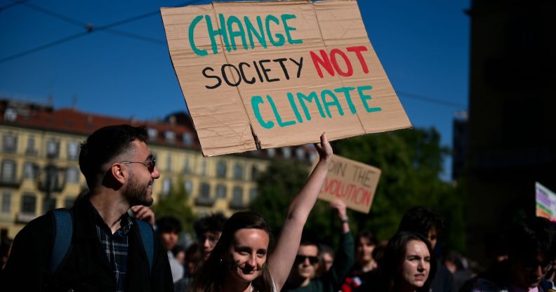 Person at a climate change march holds a sign reading "change society not climate"