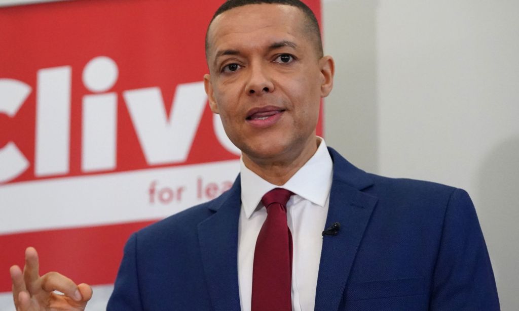 Clive Lewis, in a blue suit and red tie, speaking during an event.