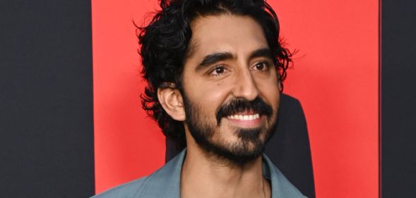 Dev Patel smiling during a red carpet event at the Monkey Man premiere.