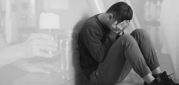 a man with his head in his hands, a bar in the background