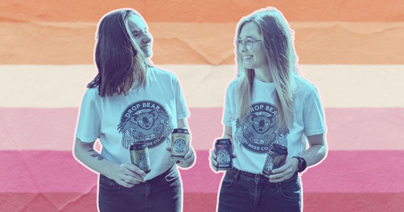 This is a creative image of two women superimposed over the lesbian pride flag. The have a blue tint effect and white outline. They are both holding two cans of beer and are smiling at each other