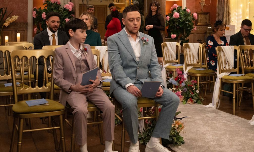 A still from ITV's soap opera Emmerdale showing out trans character Matty, played by Ash Palmisciano, sitting in a suit and tie while waiting to get married