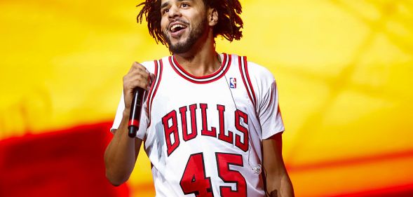 Recording artist J. Cole performs on day one of Lollapalooza on July 28, 2016 in Chicago, Illinois. He is wearing a bulls T-shirt and holding a microphone.