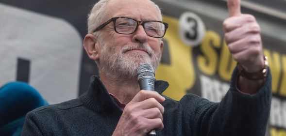 Jeremy Corbyn giving a thumbs up during a speech.