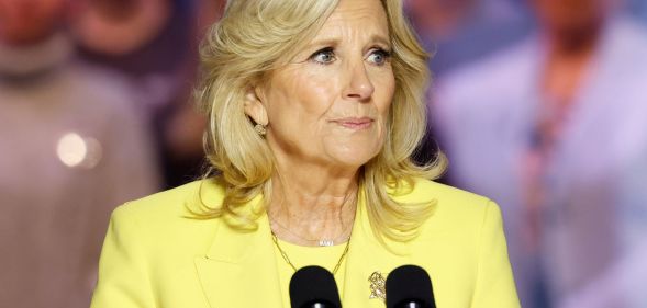 Jill Biden, wearing a yellow suit, speaks into a microphone.