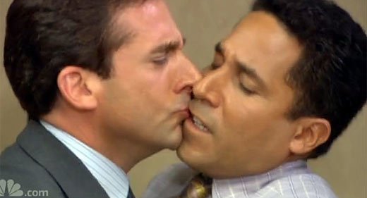 Michael Scott awkwardly kisses Oscar the accountant in a scene from The Office