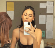 Image shows Cassandra James in the dressing room, taking a mirror selfie -wearing a strappy black top