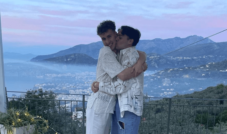 Photo shows Bradley Riches embracing his fiance in a heart shaped pattern made of roses, against a tropical backdrop on a balcony