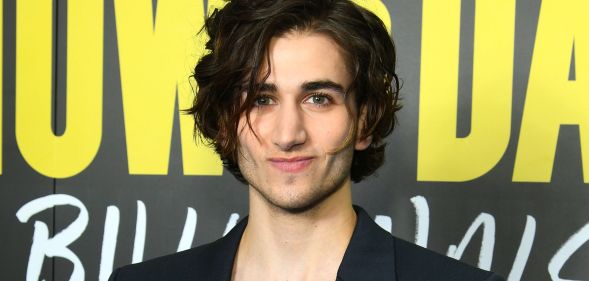 Sebastian Croft smiles while wearing a black blazer.