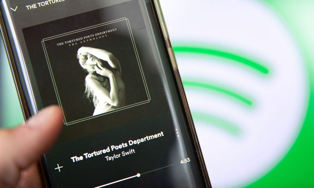 A phone playing The Tortured Poets Department by Taylor Swift, against the Spotify logo.