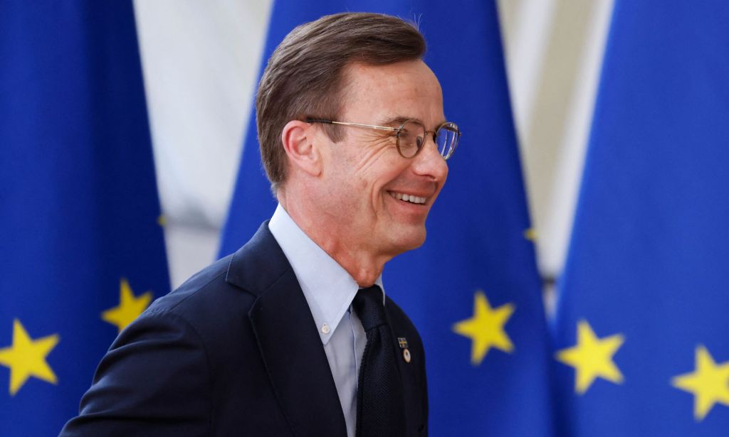 Swedish prime minister, Ulf Kristersson walking passed a set of EU flags.