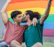 Stock image of two men kissing beneath a Pride flag
