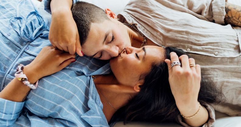 Stock image of two women kissing while lying on a sofa