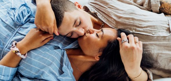 Stock image of two women kissing while lying on a sofa