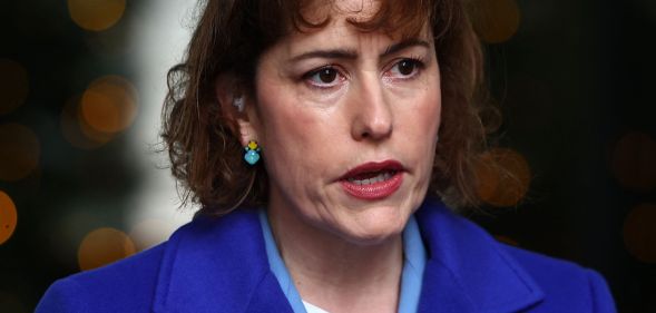 Victoria Atkins, in a blue coat, giving a speech.