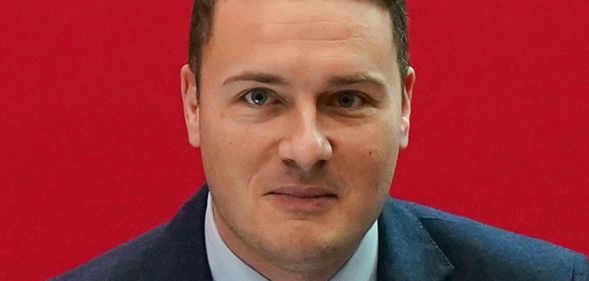 Wes Streeting at a Labour conference in front of a red background.
