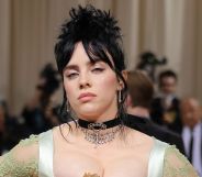 Billie Eilish with black hair done up in a bun, wearing a black choken and a strappy green dress at the 2022 MET Gala.