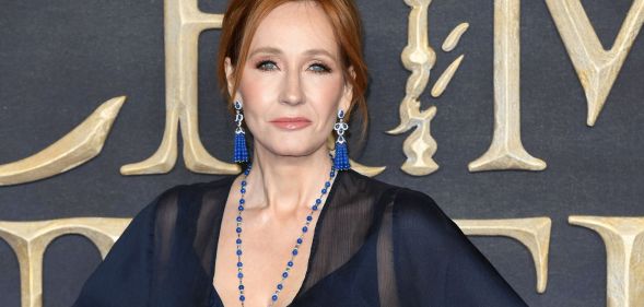 Harry Potter author JK Rowling wears a blue dress and blue jewellery as she stares towards the camera
