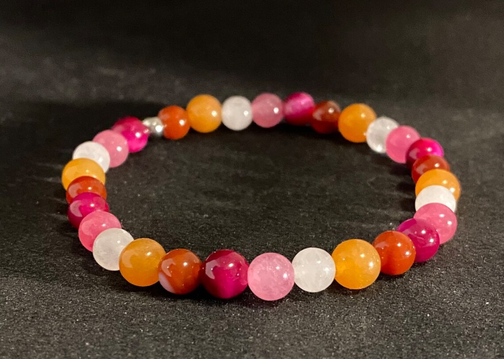 A handmade bracelet in the colours of the lesbian flag. 