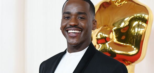 Ncuti Gatwa smiles while wearing a white shirt and black blazer.