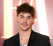 Noach Beck wears a black blazer and blue and white top with a necklace at a Vanity Fair event.