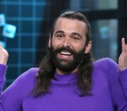 Jonathan Van Ness smiles and shrugs with their hands in the air.