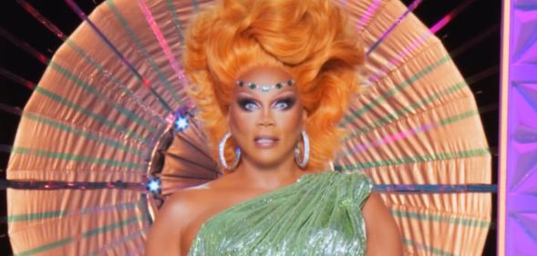 RuPaul in a green dress and orange wig on the main stage during the finale episode of drag race uk vs the world season two.