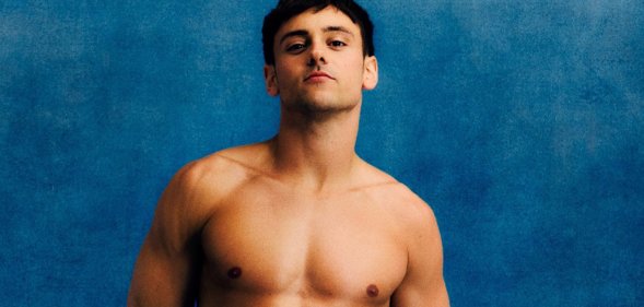 Tom Daley posing in Team GB blue swim trunks