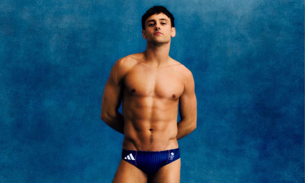 Tom Daley posing in Team GB blue swim trunks
