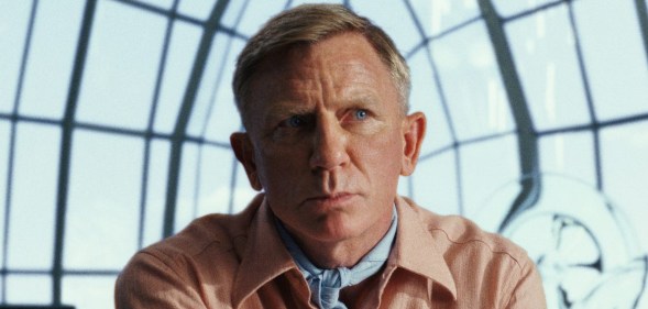 Daniel Craig in a peach suit against a window