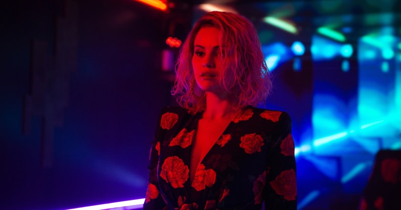 Selena Gomez lit by neon red light in Emilia Perez
