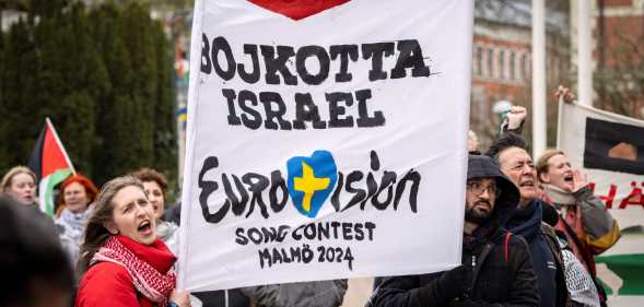 Participants hold up flags and placards during a demonstration outside the City Hall in Malmö, Sweden on April 10, 2024 in connection with the municipal board's consideration of a citizens' proposal to stop Israel's participation in the Eurovision Song Contest. The demo was organised by the citizens' initiative 'No Eurovision in Malmö with Israel's participation'. (Photo by Johan NILSSON / TT News Agency / AFP) / Sweden OUT (Photo by JOHAN NILSSON/TT News Agency/AFP via Getty Images)