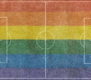 Aerial view of a grass soccer field without people and with painted white lines, with the lgtb rainbow flag painted on the grass.