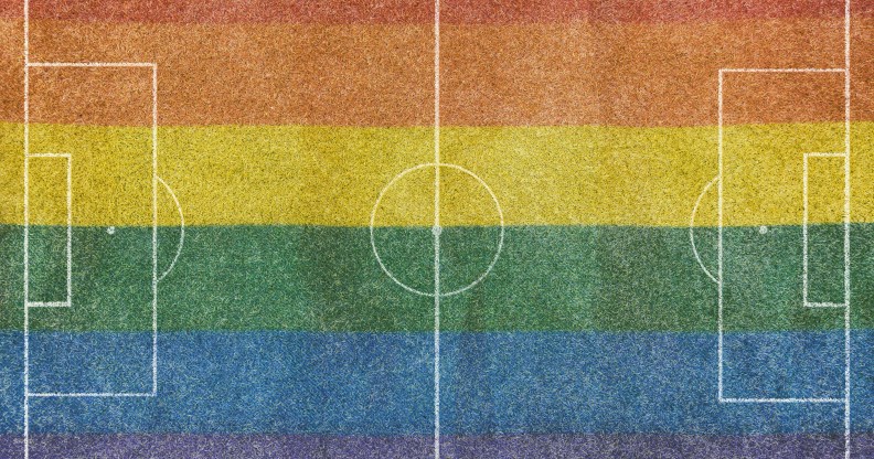 Aerial view of a grass soccer field without people and with painted white lines, with the lgtb rainbow flag painted on the grass.