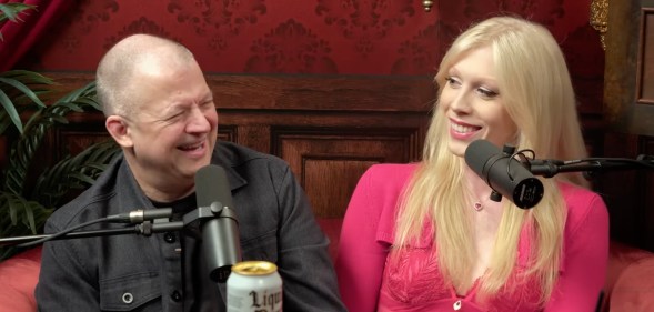 Jim and Nikki Norton sat on a red podcast sofa, both laughing