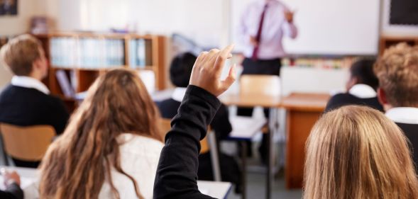 A person raising their hand in a classroom.